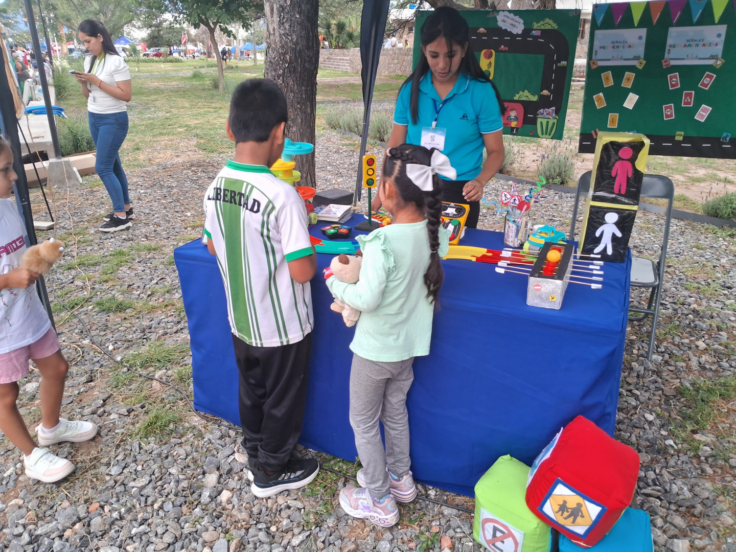 Personal de la Subsecretaría de Seguridad Vial interactúa con dos niños en el marco de las jornadas de sensibilización vial en los Valles Calchaquíes.