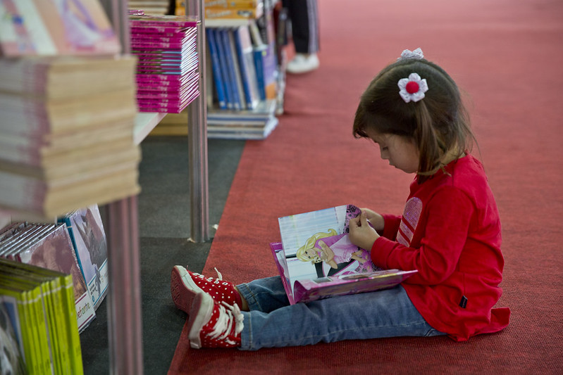Nena sentada en el piso mirando un libro