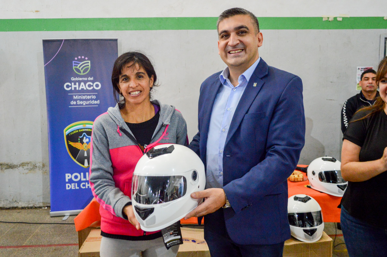 El representante de Seguridad Vial provincial entrega un casco a una participante de la clínica de conducción segura de motos.