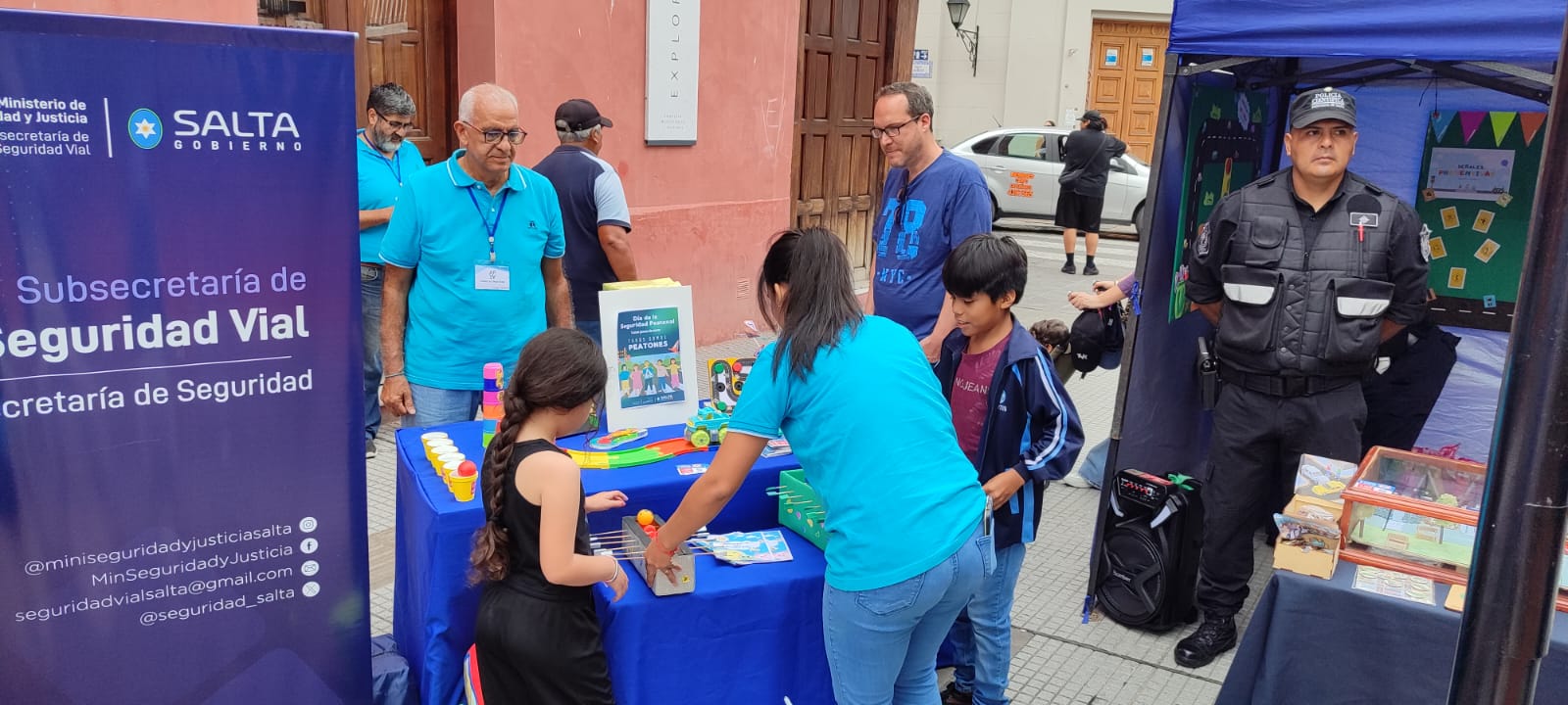 Personal de la Subsecretaría de Seguridad Vial de la provincia realiza una acción de concientización en un stand, interactuando con niños.