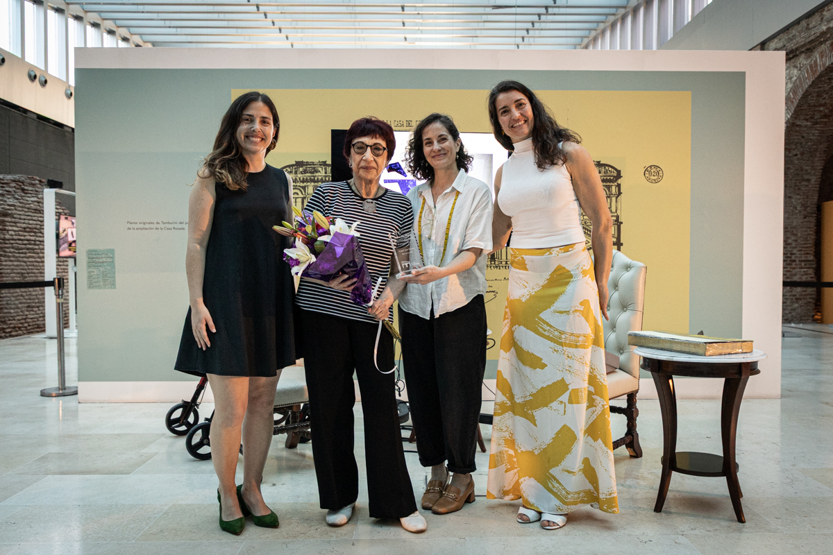 Florencia Ortolani, Alicia Díaz Rinaldi, Marcela Pupo y Spencer Prego y Virginia F. González Cuatro mujeres sonríen mirando a cámara. Se encuentran adelante de un panel y en el Patio de Maniobras del Museo Casa Rosada.