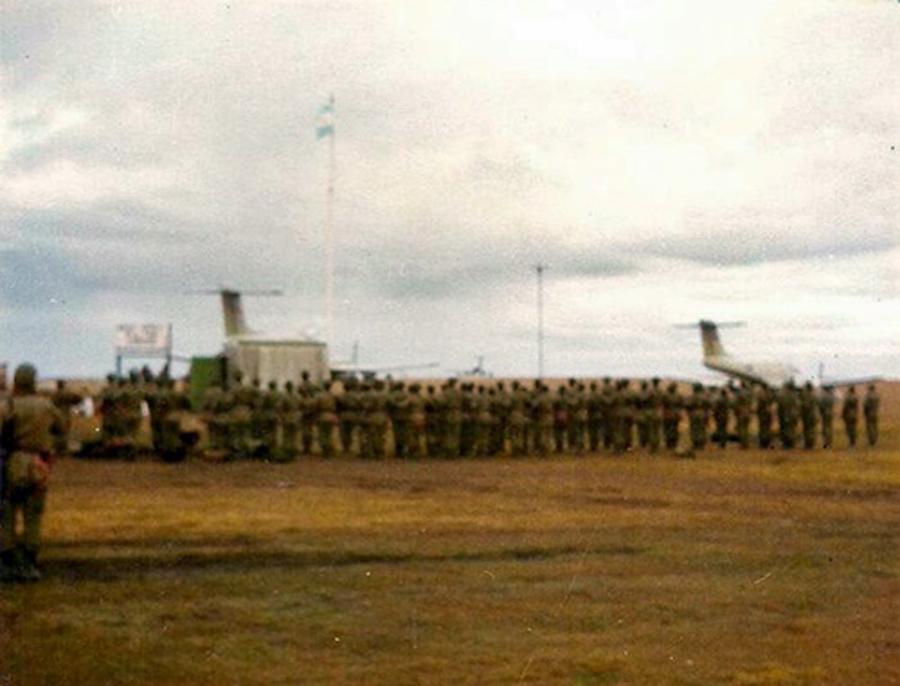 Personal de la Base Aérea Militar Cóndor entonando el Himno Nacional Argentino frente al mástil