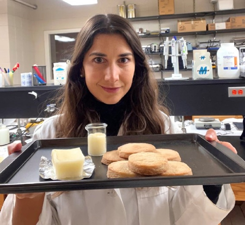 Mujer sosteniendo una bandeja con manteca y galletitas en un laboratorio