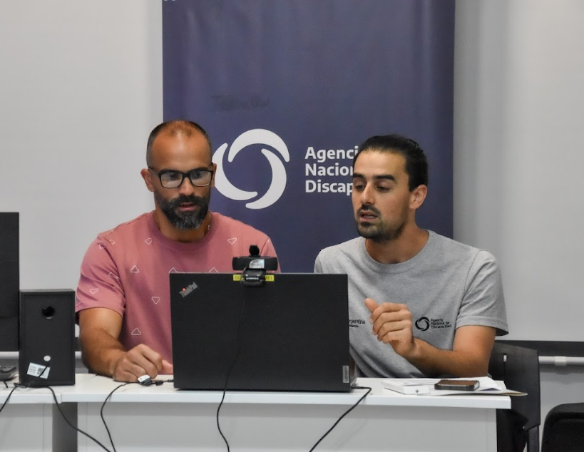 Capacitadores brindan una charla frente a una computadora