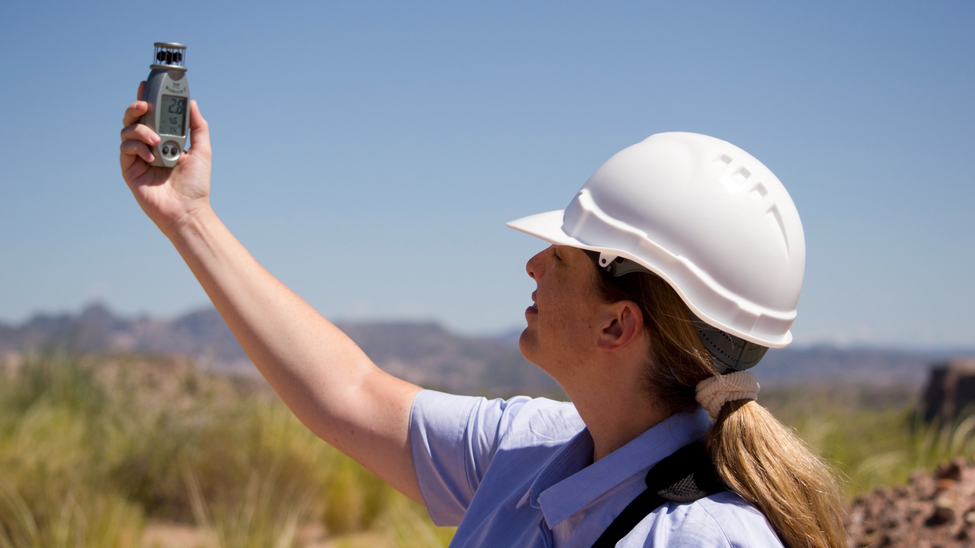 científica mujer con casco blanco mide la velocidad del viento