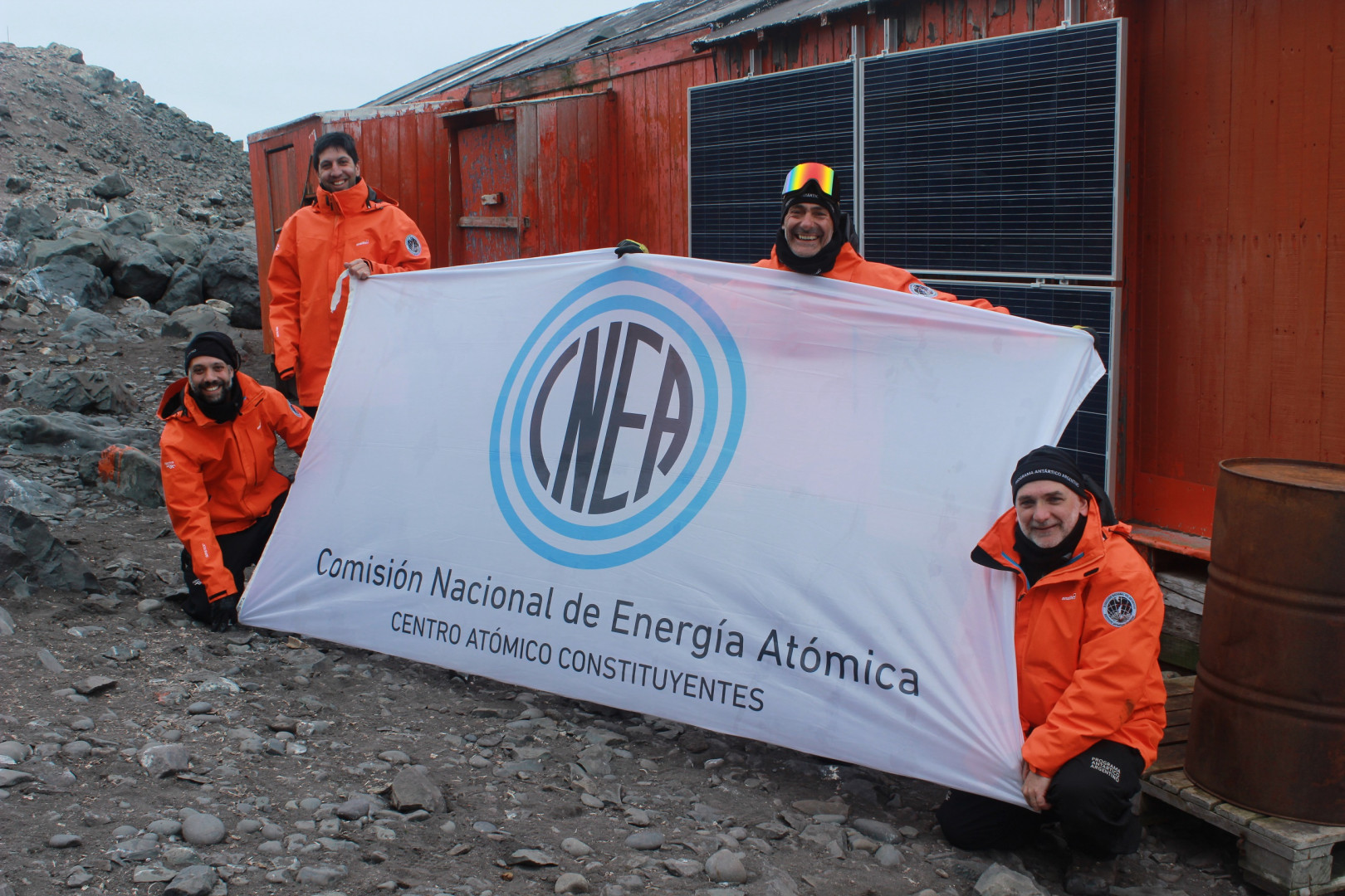Equipo del Departamento Energía Solar de la CNEA sostiene la bandera en la Antártida