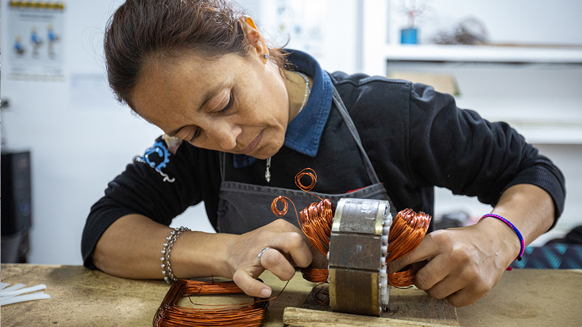 Mujer trabajadora de Cooperativa Selius con alambra de cobre en sus manos.