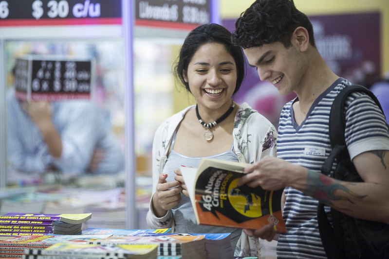 Una joven y un joven leen un libro y sonríen