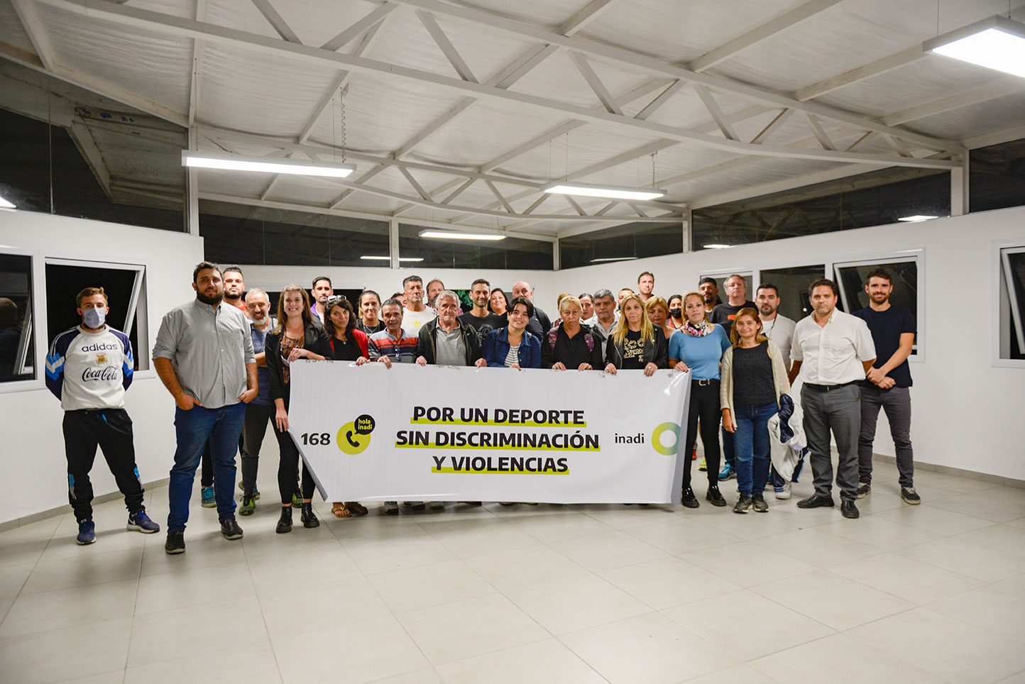 Los presentes posan con una bandera del INADI con el lema: Por un deporte sin discriminación y violencias