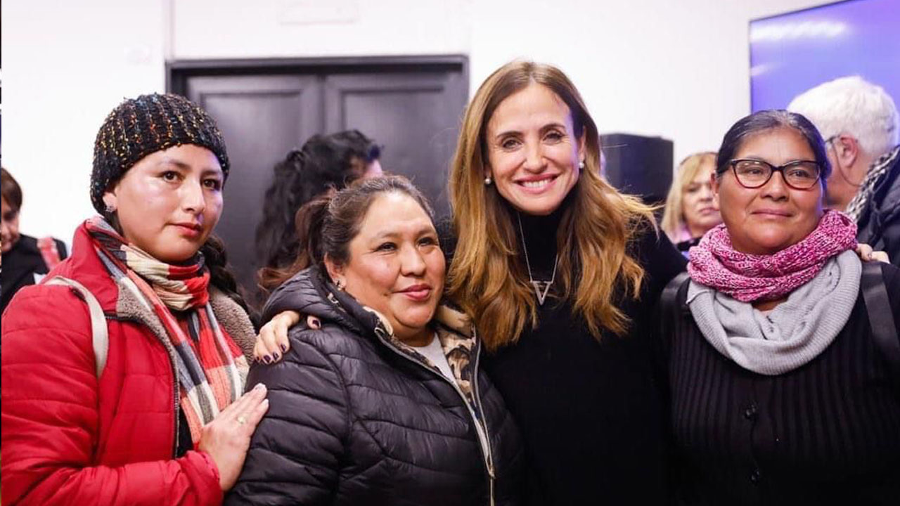 La ministra Victoria Tolosa Paz sonriendo y mirando de frente junto a tres mujeres más en el acto en la Universidad de La Plata.