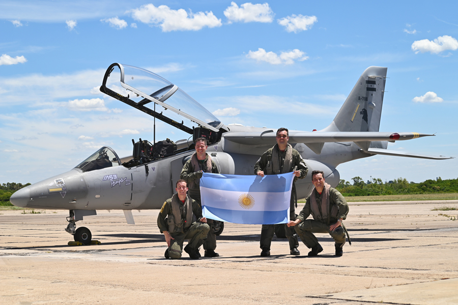 Pilotos de la Fuerza Aérea Argentina con una bandera argentina