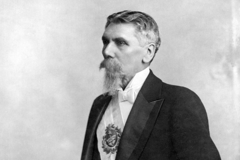 Retrato en blanco y negro del expresidente José Evaristo Uriburu. Sobre fondo claro Uriburu posa de perfil, viste frac y lleva la banda presidencial sobre su pecho.