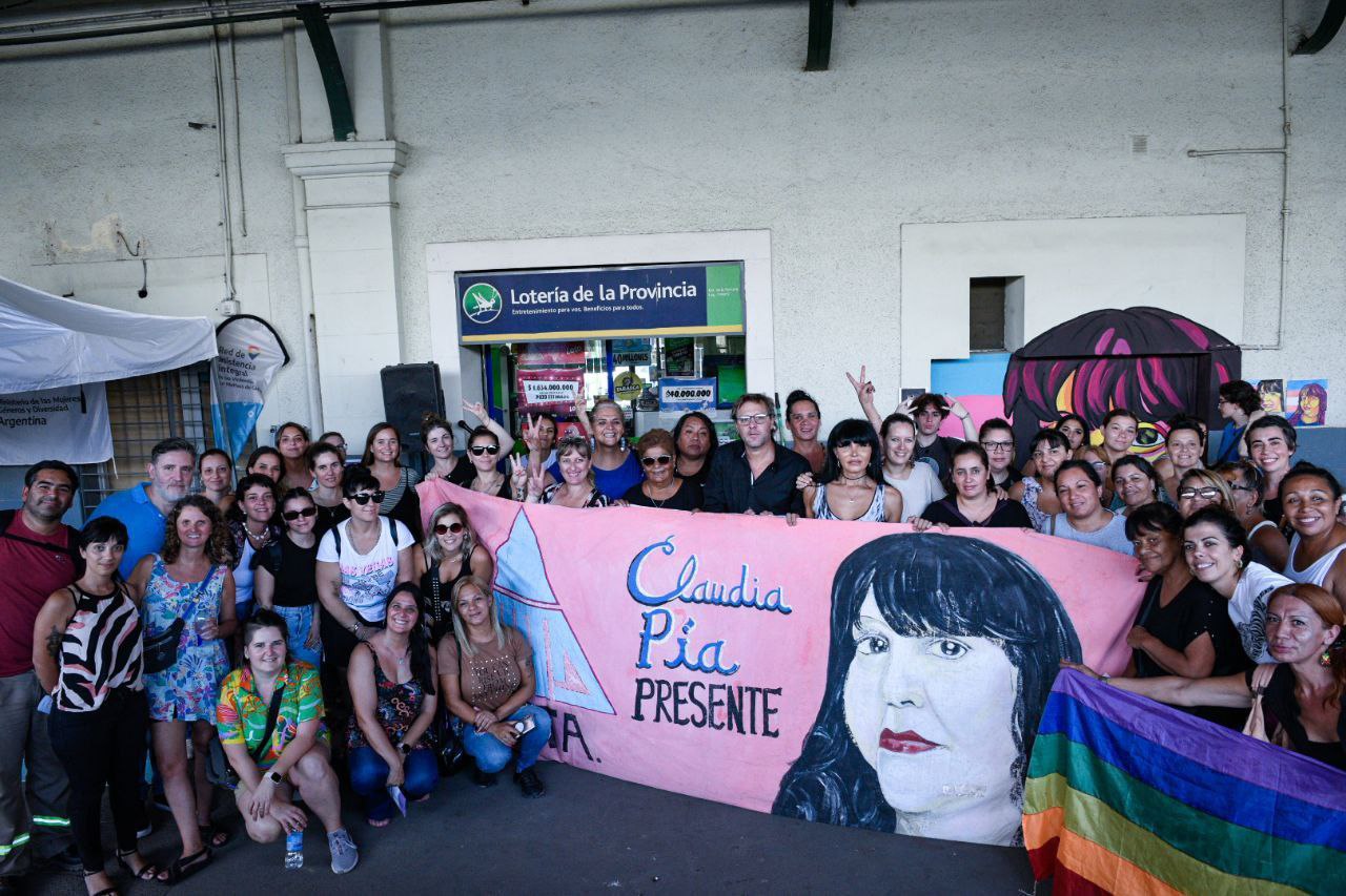 Un grupo de personas sostiene una bandera con la imagen de Claudia Pía Baudracco