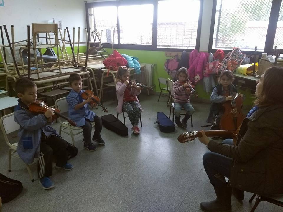 Niños tocando instrumentos con un profesor