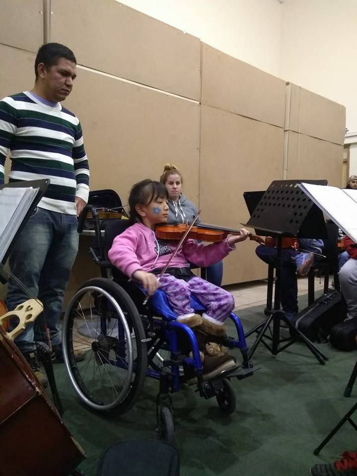 Niña en silla de ruedas tocando el violín