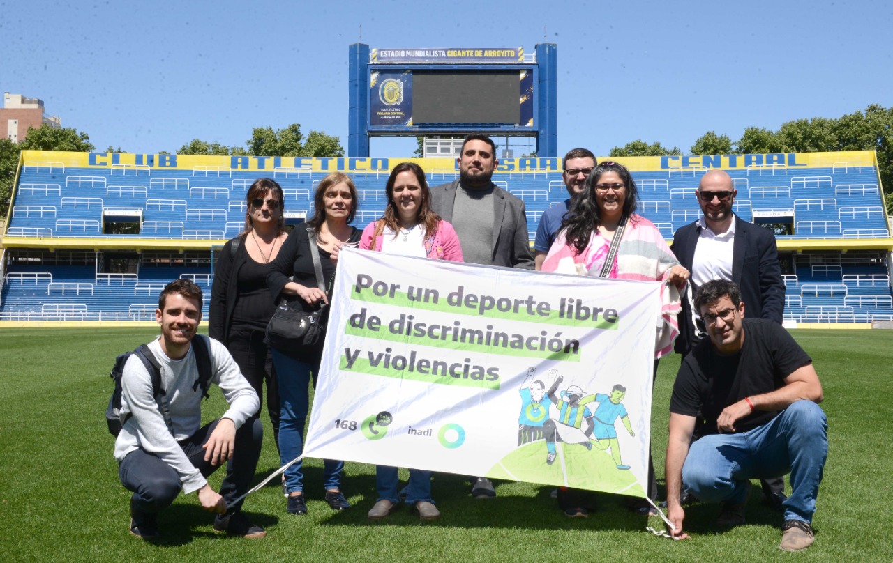 Las personas que participaron en la capacitación posan con una bandera del INADI con el lema: "Por un deporte sin discriminación y violencias".