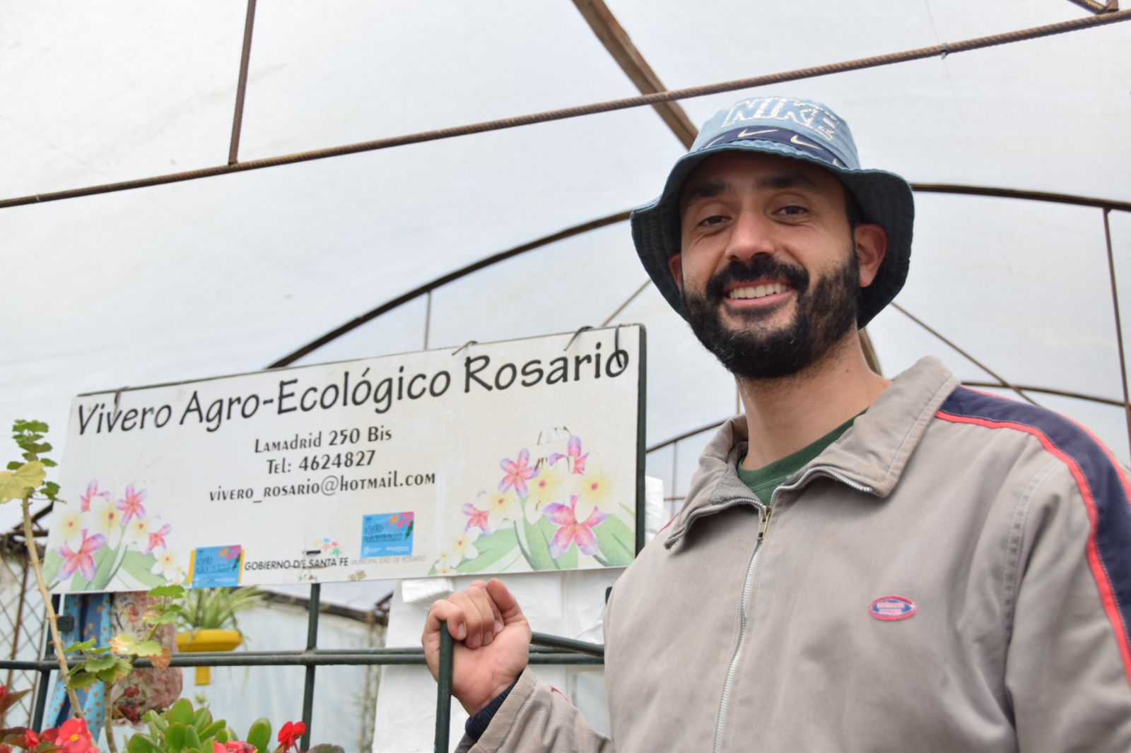 Imágen de un hombre dentro del vivero agroecológico de Rosario, con el cartel de dicho vivero detrás de él,