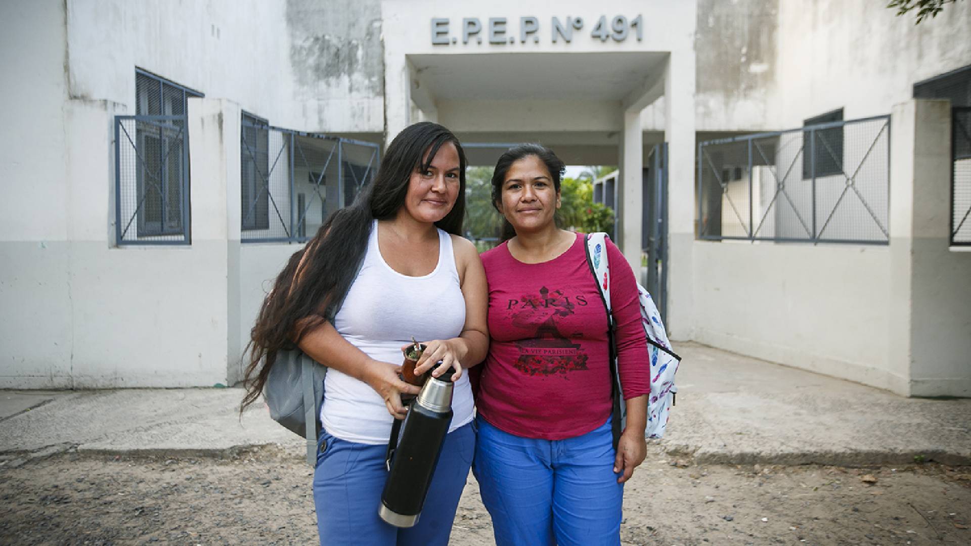 Dos mujeres titulares de Potenciar Trabajo que están estudiando a través de la iniciativa "Volvé de Estudiar" en la puerta de su escuela. 