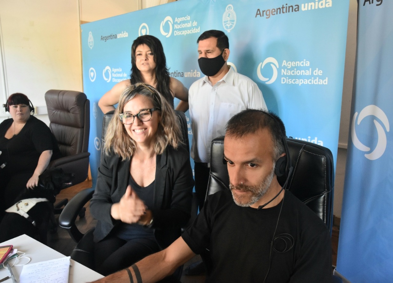 Imágen de autoridades de la ANDIS junto con la interprete en Lengua de Señas Argentina asistiendo mediante videollamada a una persona con discapacidad.