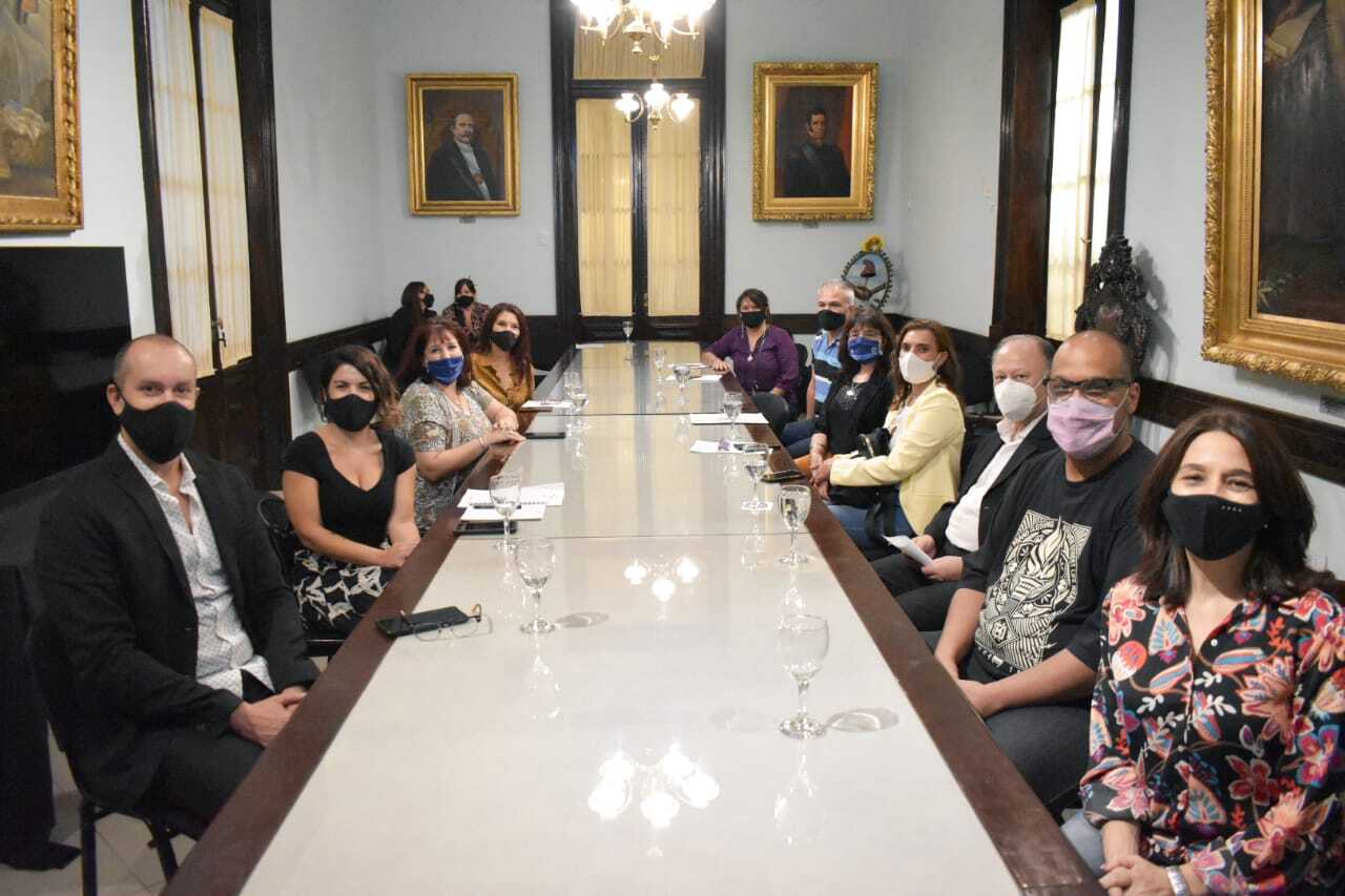 Personas sentadas en una mesa larga mirando a cámara.