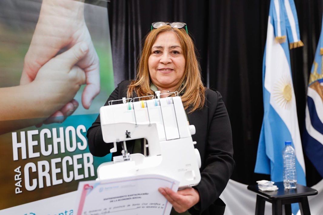 Mujer emprendedora sonriendo con su nueva máquina de coser que obtuvo a través del banco de máquinas y herramientas.