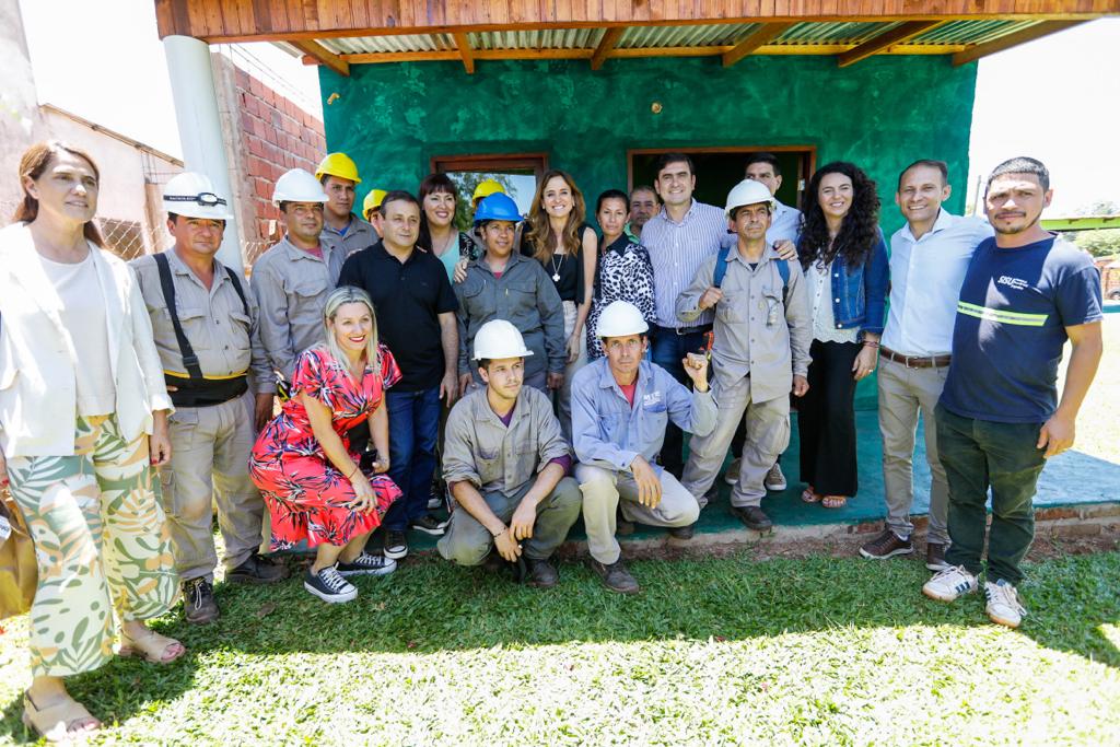 Hombres y mujeres cooperativistas con ropa y casco de trabajo junto a la ministra Victoria Tolosa Paz y funcionarios locales.