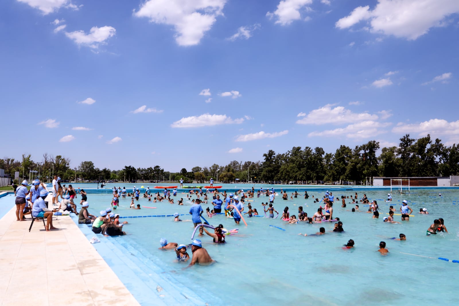 Vista de la gigantesca pileta de natación del predio de Ezeiza con niños en el agua disfrutando.