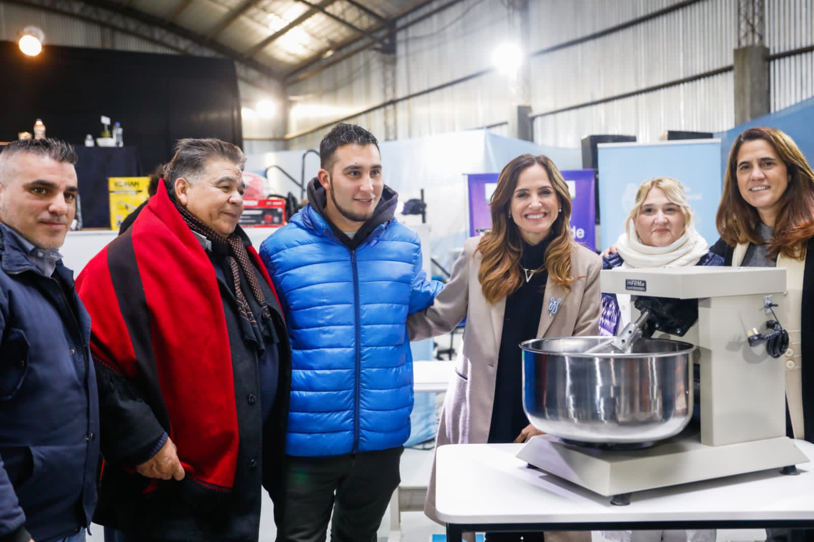 La ministra Victoria Tolosa Paz junto al intendente Mario Ishii y la directora Natalia Mainoldi entregando máquinas a titulares del programa Talleres Familiares.