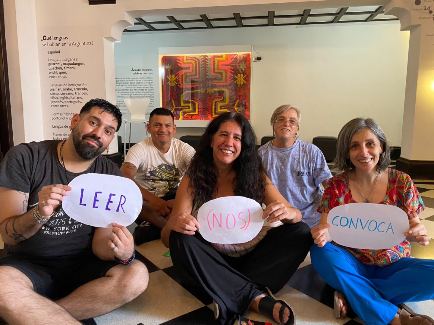 Grupo de personas con el cártel "Leer nos convoca en la mano"