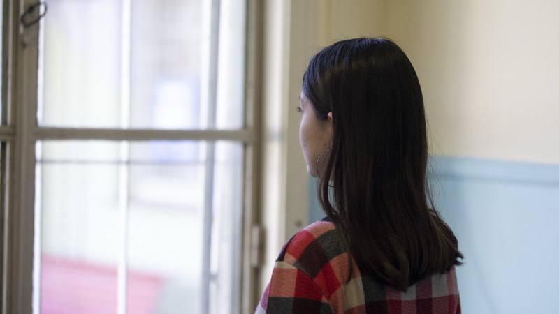Una chica adolescente está mirando por una ventana.